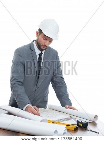 Constructions plan. Vertical studio shot of a male architect in a protective helmet drawing up building plan on blueprint isolated on white professionalism experience confidence success businesspeople