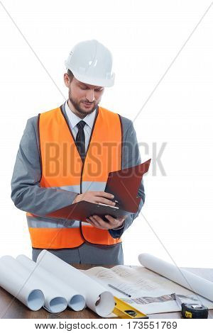Constructionist businessman. Mature male constructionist wearing safetu vest and a hardhat making notes on his clipboard isolated on white professionalism development confidence experience concept