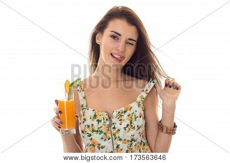 a charming young girl in Sarafan winks and holds in her hand a glass of orange juice is isolated on a white background
