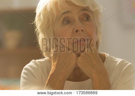Close-up of pretty worried senior woman sitting alone