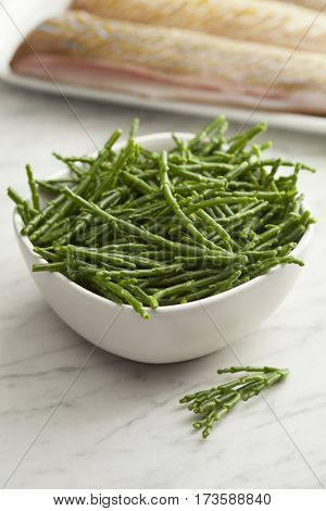  Fresh raw green samphire in a bowl with fresh fish in the background