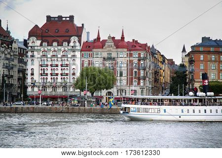 STOCKHOLM SWEDEN - AUGUST 20 2016: Many people walk and visit on Strandvagen street on Ostermalm distric with touristic sightseeing boats in Stockholm Sweden on August 20 2016.