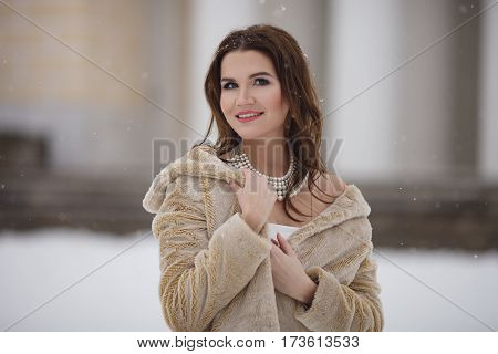Young girl in a fur coat on eco background old building