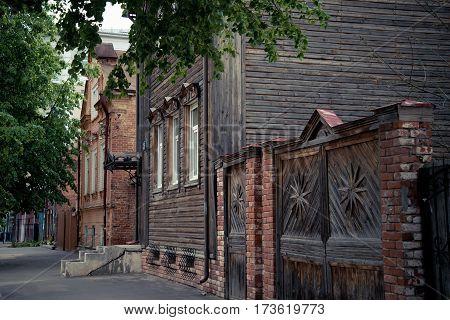 The beautiful old street with old wooden and brick houses with a porch in the city