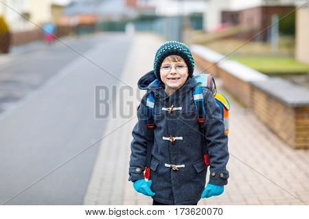 Little kid boy with eye glasses walking from the school. Child on a street. Preschooler wearing warm spring, autumn or winter clothes, glasses and backpack. Happy student or people. Education concept