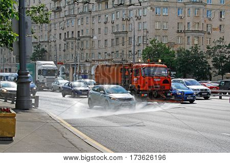 Moscow Russia - June 02 2016: Street flusher machine and vehicles riding on the road in the city. Watering machine washes the road dust and dirt