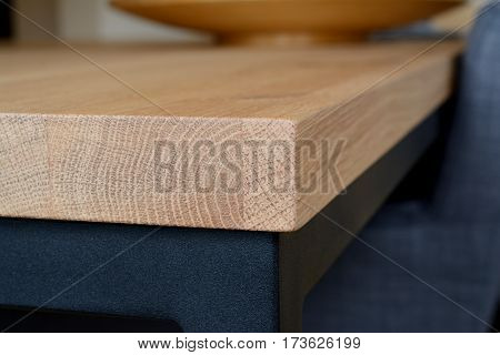 Corner of wooden table top made of oak wood closeup. Table top on black steel frame. Shallow depth of field.