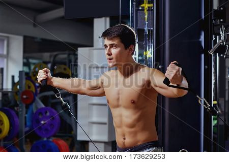 Man with a sports figure doing exercise on  simulator in the gym.