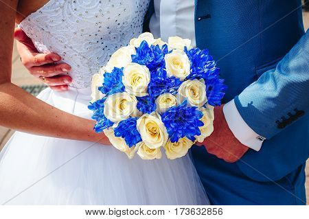 Bride blue and beige flowers bouquet in hands