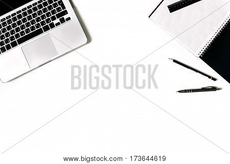 White office desk frame with paper blank and supplies. Laptop, notebook, pen, clips, glasses and office supplies on white background. Flat lay, top view, mockup.