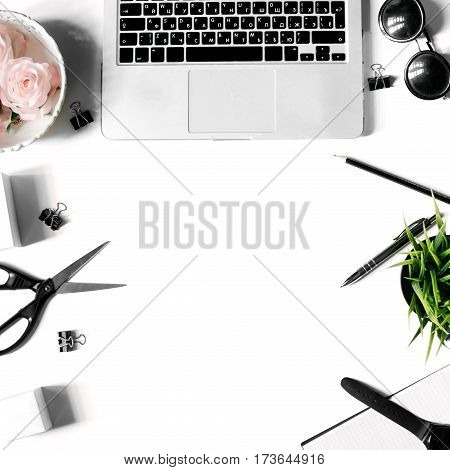 White office desk frame with laptop keyboard and supplies. Laptop, notebook, pen, roses, sunglasses, clips, pencil, plant, scissors, watch and office supplies on white background. Flat lay, top view, mockup