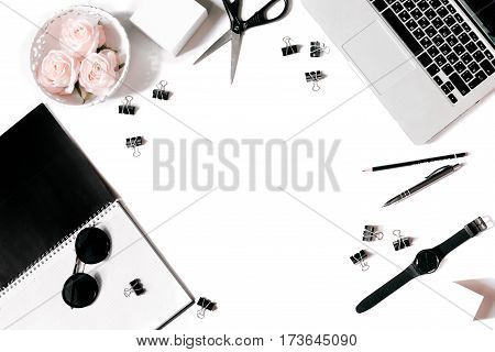 White office desk frame with laptop keyboard and supplies. Laptop, notebook, pen, roses, sunglasses, clips, pencil, scissors, watch and office supplies on white background. Flat lay, top view, mockup