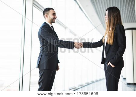 Businessman and Businesswoman handshake in office with big panoramic windows