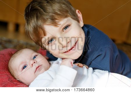 Close-up portrait of happy little kid boy with newborn baby girl, cute sister. Siblings. Brother and baby cuddling together. Kids bonding. Family of two bonding, love.