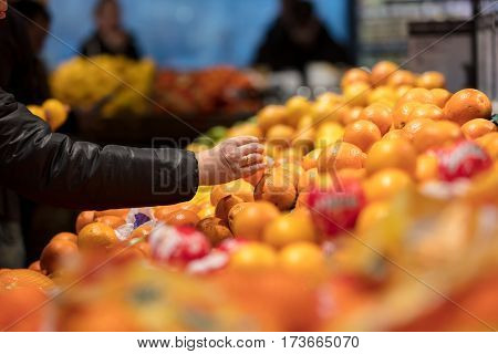 female's hand pick up Sunkist orange in market