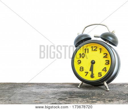 Closeup black and yellow alarm clock for decorate show half past six or 6:30 a.m. on old brown wood desk isolated on white background with copy space