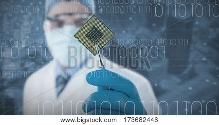 Doctor holding electronic chip with forceps against electronic circuit board with processor