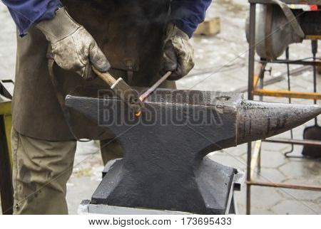 Detail shot of hammer forging hot iron at anvil.