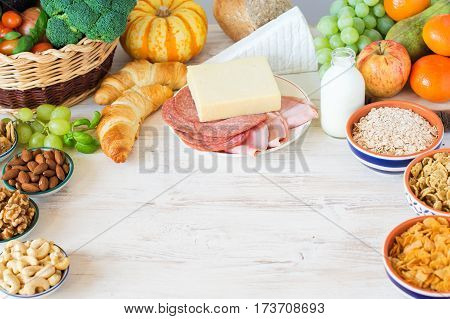 Variety of fruits and vegetables nuts cereals ham cheese on the white wooden table selecitve focus