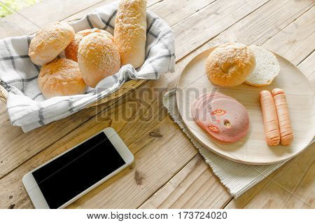 Breakfast with bread cheese sausage baloney sausage and smart phone