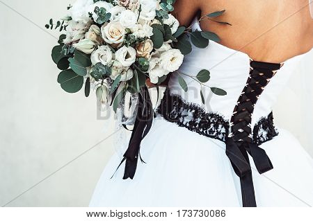 bride in a luxurious wedding dress with a black lace holding a wedding bouquet decorated with a black ribbon made of roses