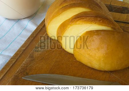cut head of traditional Adygei cheese handmade with knife on wooden Board