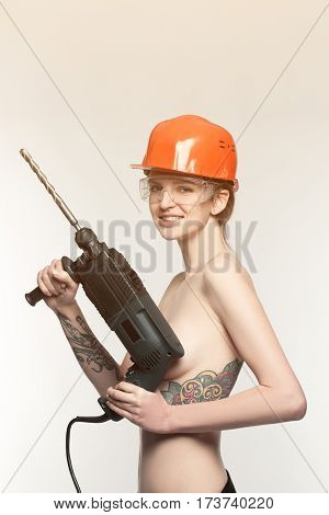 woman nude with drill in arms in orange construction helmet isolated in white background.