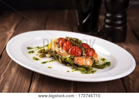 Grilled trout with tomatos leguminous beans and lemon on white plate. Top view