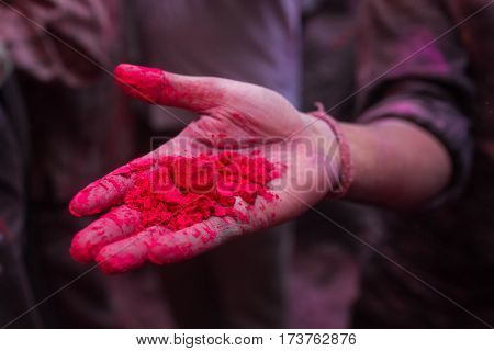 Hand with powdered red dye during for Holi celebration in India. Detail shot