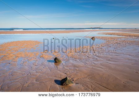 Shipwreck remains on Bamburgh Beach, at low tide just below Bamburgh Castle lies an unknown wooden shipwreck overlooked by the Farne Islands on the horizon