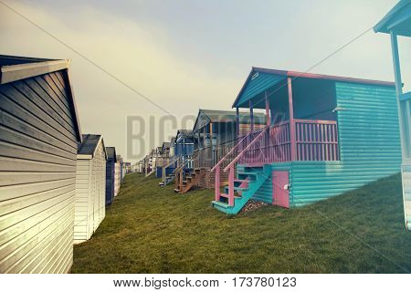 Row of colored beach huts with stormy blue sky on the beach of Tankerton near Whitstable in Kent, UK