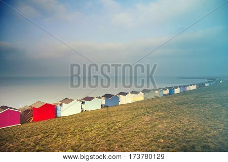 Row of colored beach huts with stormy blue sky on the beach of Tankerton near Whitstable in Kent, UK