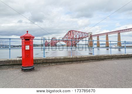 Red letterbox and Firth of Forth rail bridge in Edinburgh, Scotland UK