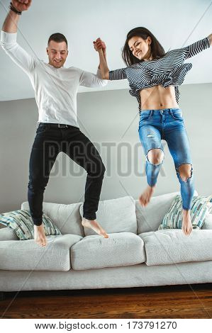 Portrait of young beautiful funny couple man woman in love having fun jumping from bed indoors at home authentic lifestyle with real people toned with filters motion blur effect