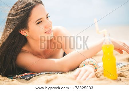 Beach woman drinking cold drink beverage having fun at beach party. Female babe in bikini enjoying orange water from glass boutle. summer concept