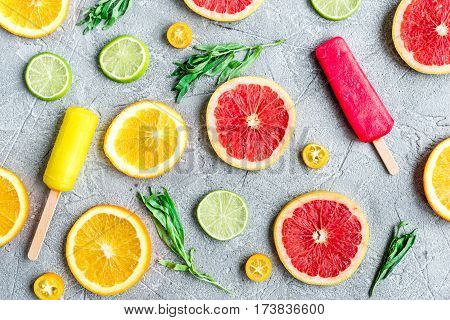 fresh citrus slices with fruit popsicles on stone table background top view pattern