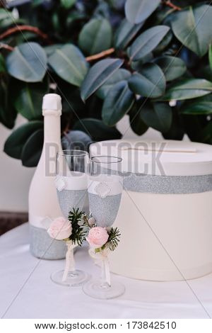 Two decorated with boutonieres newlyweds glasses and bottle of champagne on the wedding celebration