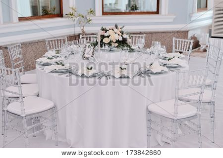 Well decorated guest numbered table in tenderless wedding hall, which is in white and silver colours