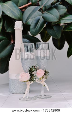 Two decorated with boutonieres newlyweds glasses and bottle of champagne on the wedding celebration