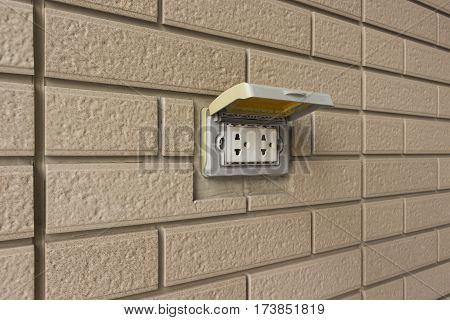 A Socket with cover for outdoor in a brick wall