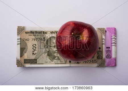 indian new currency notes of 500 and 200 rupees with fresh red apple and stethoscope - India and healthcare concept