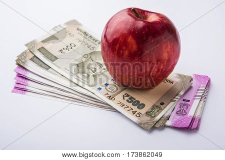 indian new currency notes of 500 and 200 rupees with fresh red apple and stethoscope - India and healthcare concept