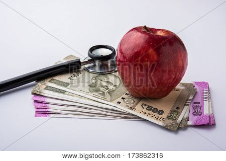 indian new currency notes of 500 and 200 rupees with fresh red apple and stethoscope - India and healthcare concept