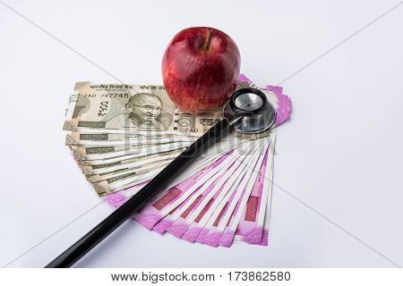 indian new currency notes of 500 and 200 rupees with fresh red apple and stethoscope - India and healthcare concept