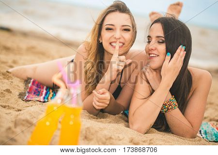Gierlfriends drinking cold drink beverage having fun at beach party. Female babes in bikini enjoying orange water from glass boutle. summer concept