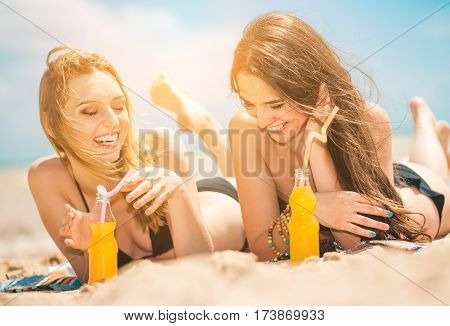 Gierlfriends drinking cold drink beverage having fun at beach party. Female babes in bikini enjoying orange water from glass boutle. summer concept