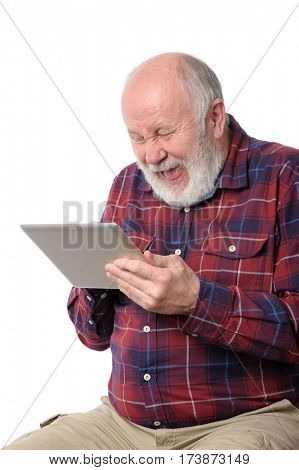 Senior bald and bearded white haired man laughing loud with something at screen of tablet computer, isolated on white background