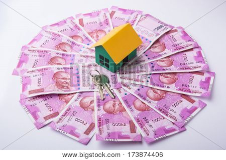 indian real estate or residential model house with new currency notes, keys, toy car and calculator, selective focus