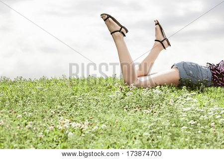 Low section of woman lying on grass against sky