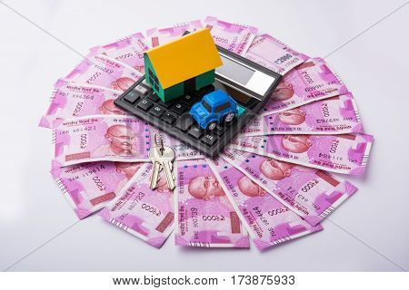 indian real estate or residential model house with new currency notes, keys, toy car and calculator, selective focus